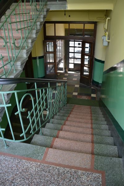 Sień oraz klatka schodowa kamienicy to prawdziwy unikat i uczta dla oka. Ściany sieni, cok&oacute;ł ścian, posadzki oraz stopnie wyłożone są szlifowanym wielobarwnym terrazzo, tworzącym ciekawe kompozycje geometryczne. Z oryginalnego wyposażenia wnętrza sieni i klatki schodowej  zachowały się do dziś w bardzo dobrym stanie także stylizowane metalowe balustrady oraz stolarka drzwiowa z mosiężnymi okuciami i szkłem wzorzystym. Zdjęcie ze zbior&oacute;w Biura Miejskiego Konserwatora Zabytk&oacute;w UM Rzeszowa